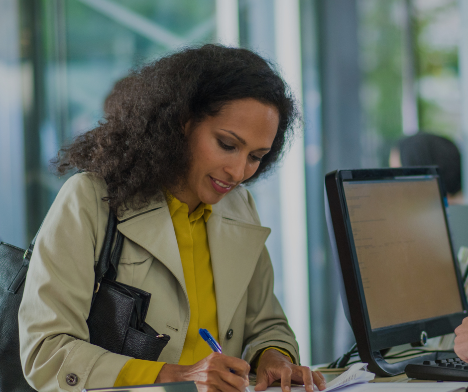 Customer at a retail bank branch smiling while standing at the counter to represent how Pathstream university certificate programs for retail branch teams result in happier customers.